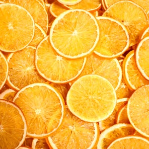Flat lay with many dried orange slices showing natural color and texture. Perfect dried citrus slices for eco home decor, handmade crafts, or cocktail garnish. Made from real dried natural fruits.