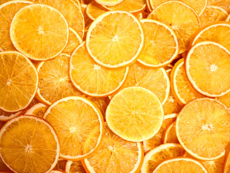 Flat lay with many dried orange slices showing natural color and texture. Perfect dried citrus slices for eco home decor, handmade crafts, or cocktail garnish. Made from real dried natural fruits.