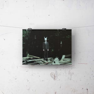 May include: A person wearing a white rabbit mask and a dark suit stands in a dark forest setting. The person is standing on a pile of wooden planks.