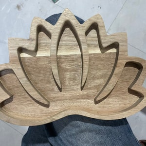 May include: A wooden tray shaped like a lotus flower with three carved out sections. The tray is made of light brown wood and has a natural finish.