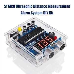 May include: A clear acrylic case houses a blue circuit board with electronic components, including a digital display showing "385". The device includes ultrasonic sensors and is labeled "51 MCU Ultrasonic Distance Measurement Alarm System DIY Kit".