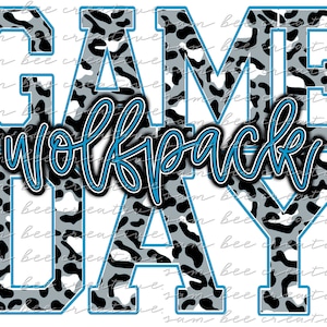 Könnte beinhalten: Weiße Buchstaben, die "GAME DAY" buchstabieren, mit einem blauen Umriss. Die Buchstaben sind mit einem schwarz-weißen Leopardenmuster gefüllt. Das Wort "Wolfpack" ist in blauer Kursivschrift über den Buchstaben geschrieben.