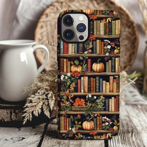 May include: A black phone case with a design of a bookshelf filled with books, pumpkins, and fall foliage. The case has a cutout for the phone's camera.