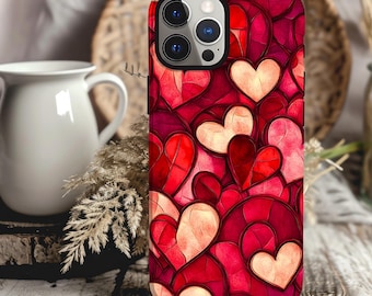 May include: A red, pink, and white phone case with a pattern of hearts. The case is designed for an iPhone with a camera lens cutout.