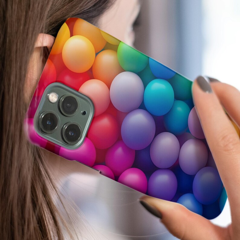 May include: A colorful phone case with a pattern of rainbow-colored balls. The case is designed for an iPhone with a triple lens camera.