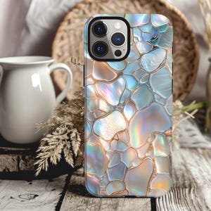 May include: A phone case with a iridescent, abstract pattern of blue, white, and gold. The case has a raised camera bump with three lenses.