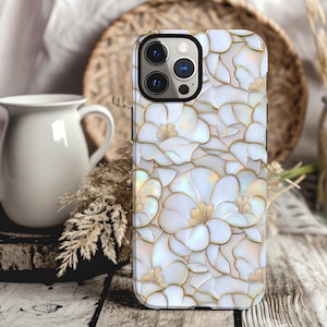 May include: White iPhone case with a floral design featuring white flowers with gold outlines on a white background.