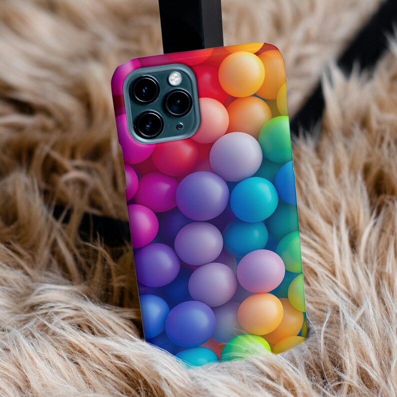 May include: A colorful phone case with a pattern of rainbow-colored balls. The case has a black camera lens cutout.