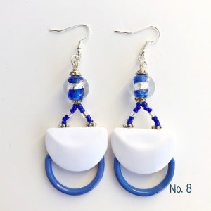 May include: White and blue dangle earrings with a silver and blue glass bead, blue beads, and a white ceramic crescent moon shape. No. 8