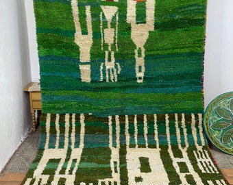 May include: A green and white Moroccan rug with a geometric pattern. The rug has a fringe border and is made of wool.