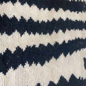 May include: Black and white zig zag patterned rug with a fluffy texture.