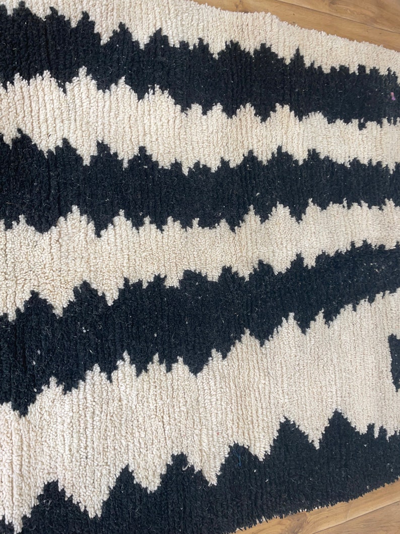 May include: Black and white zig zag patterned rug with a fluffy texture.