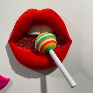 May include: Red lips with glitter inside, biting down on a colorful striped lollipop with a white stick.