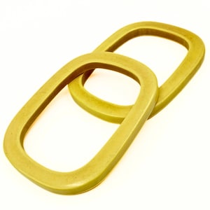 May include: Two interlocking, olive-green, oval-shaped objects. The objects are made of a solid material and have rounded edges. The background is plain white, providing a clean contrast to the objects.