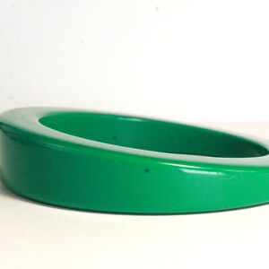 May include: A bright green plastic bangle bracelet. The bracelet is thick and has a rounded shape.