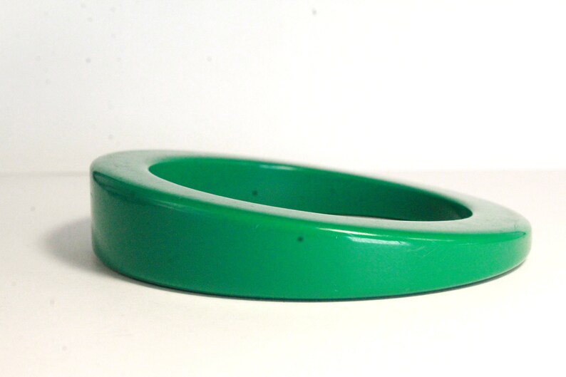 May include: A bright green plastic bangle bracelet. The bracelet is thick and has a rounded shape.