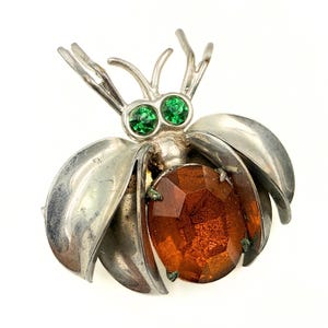 Broche ancienne Art Déco en métal et verre brun-vert représentant un pot à insectes