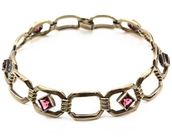 May include: A gold-toned bracelet with a chain link design and pink gemstone accents.