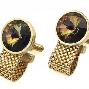 May include: A pair of gold cufflinks with a round, faceted, brown and green gemstone in the center. The cufflinks have a chain-link design.