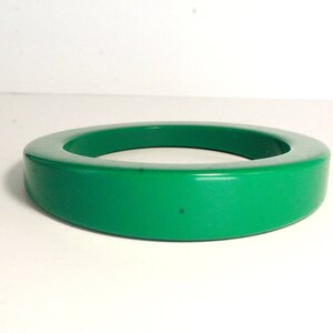 May include: A bright green plastic bangle bracelet. The bracelet is thick and has a rounded shape.