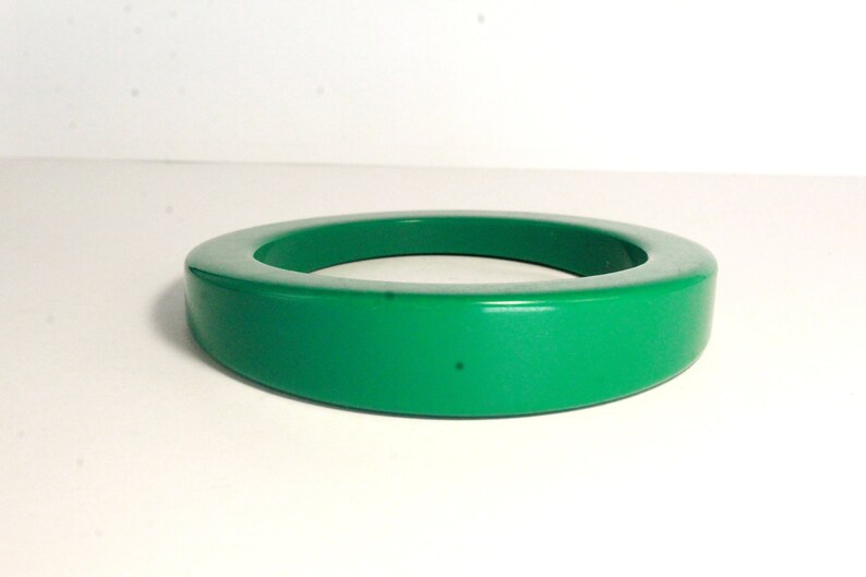 May include: A bright green plastic bangle bracelet. The bracelet is thick and has a rounded shape.