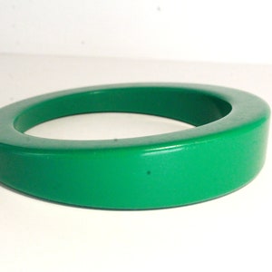 May include: A bright green plastic bangle bracelet. The bracelet is thick and has a rounded shape.