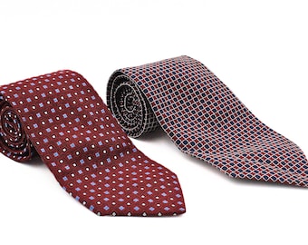 May include: Two rolled neckties. One is a deep burgundy with small blue and white squares. The other is a similar pattern, but with a navy and red grid design. Both ties are on a white background.