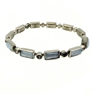 May include: Silver-toned bracelet featuring rectangular and round beads. The bracelet has a vintage look, with rectangular, light blue-gray stones set between the metal beads. A delicate piece of jewelry.