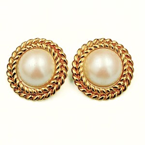 May include: A pair of round earrings featuring a central white faux pearl cabochon surrounded by a textured gold-tone metal border with a twisted rope design. The circular earrings have a polished finish and a classic, symmetrical appearance.