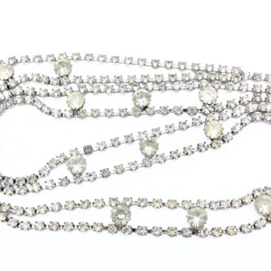 May include: A silver chain necklace with multiple strands of clear rhinestones.