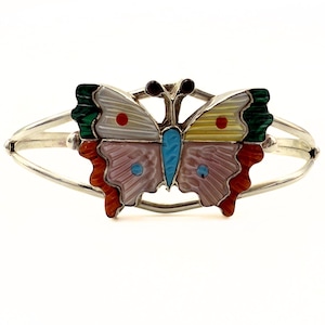 May include: A silver-coloured hinged cuff bracelet featuring a butterfly design. The butterfly's wings are multi-coloured, including white, yellow, pink, green, and orange, with a turquoise body. The bracelet is a hinged cuff style.