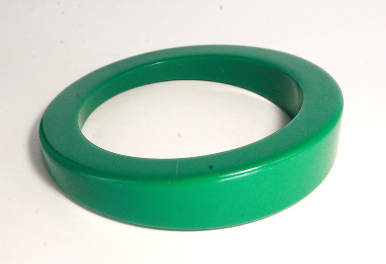 May include: A bright green plastic bangle bracelet. The bracelet is thick and has a rounded shape.