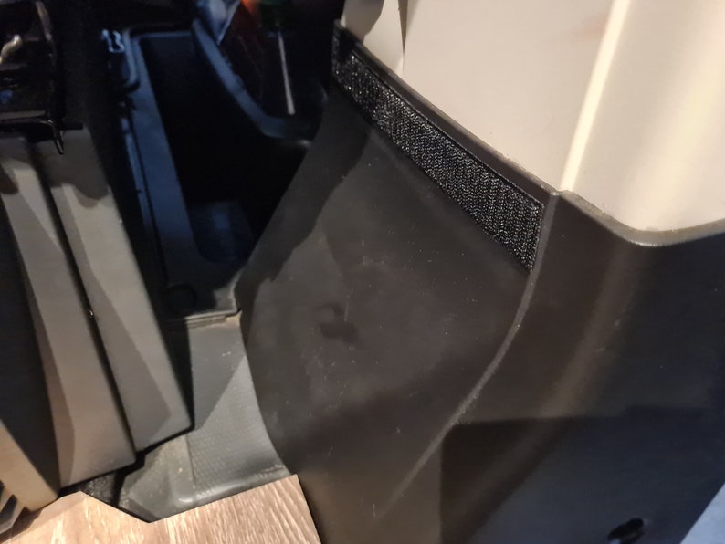 Pode incluir: Close-up de um painel de pl&aacute;stico preto com uma tira de velcro preto.