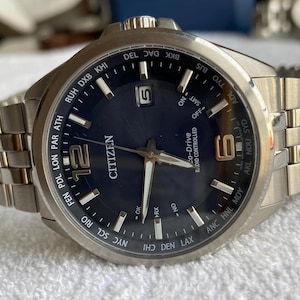 Può includere: Orologio da polso Citizen Eco-Drive radiocontrollato con quadrante blu scuro e cinturino in metallo argentato. L'orologio presenta l'indicazione della data alle 5 e indicatori di fusi orari multipli. Le lancette e gli indici sono argentati.