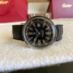 Puede incluir: Un reloj vintage LIP Nautic-Ski Electronic con esfera negra y ventana de fecha a las 3. El reloj tiene caja de acero inoxidable, correa de cuero negro y dos coronas grandes. La esfera muestra los números 10, 20, 30, 40 y 50.