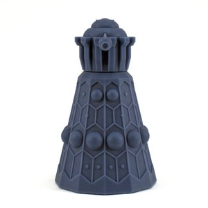 Może przedstawiać: Niebieski plastikowy model Daleka, fikcyjnego robota z brytyjskiego serialu science fiction Doctor Who. Dalek ma cylindryczny kształt z kopułą na górze i działem z przodu.