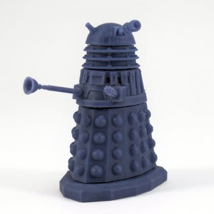Könnte beinhalten: Ein blaues Plastikmodell eines Daleks, ein fiktiver Roboter aus der britischen Science-Fiction-Fernsehserie Doctor Who. Der Dalek hat einen kuppelförmigen Kopf mit einem einzigen Auge, einen zylindrischen Körper mit einer drehbaren Basis und einen langen, dünnen Arm mit einer Waffe am Ende.