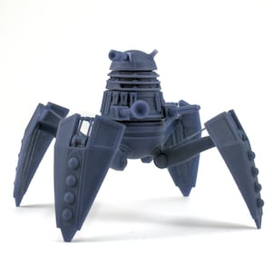 May include: A blue and gray plastic model of a Dalek, a fictional robot from the British science fiction television series Doctor Who. The Dalek is on a tripod stand with three legs.