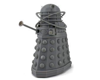 May include: A gray Dalek figurine, a fictional extraterrestrial race from the British science fiction television program Doctor Who. The figurine has a cylindrical body with numerous round, gray protrusions and a gun-like arm.