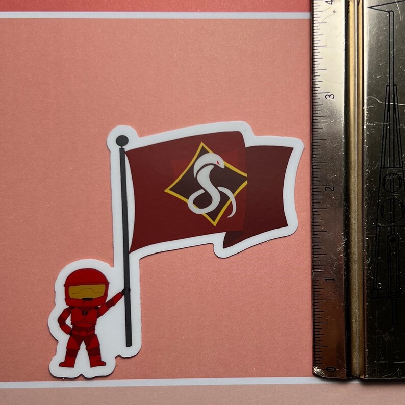 May include: A red and white cartoon character holding a flag with a red background and a white snake in a diamond shape. The snake is curled up and has a white head and tail.