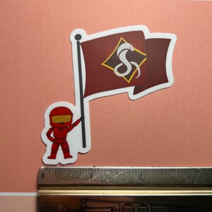 May include: A red and white sticker featuring a cartoon character holding a flag with a white snake logo on a maroon background. The flag has a white border and the snake logo is inside a diamond shape.