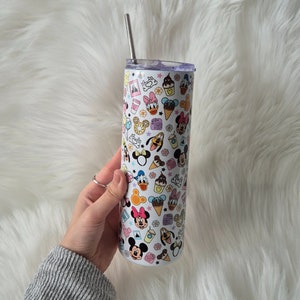 May include: A white stainless steel tumbler featuring a colourful pattern of Disney characters, including Mickey Mouse, Minnie Mouse, Donald Duck, Goofy, and Pluto. The tumbler has a straw and a lid.
