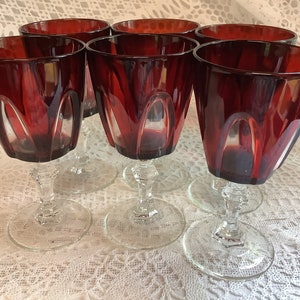 Puede incluir: Juego de seis copas de vino tinto rubí con tallos y bases de vidrio transparente. Las copas tienen un diseño facetado.