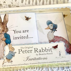 Puede incluir: Un juego de invitaciones de Peter Rabbit en caja. La caja presenta ilustraciones de Peter Rabbit y un pato con gorro. El texto "You are invited" se muestra en las tarjetas. La caja también incluye el texto "The Original Peter Rabbit by Beatrix Potter Invitations".
