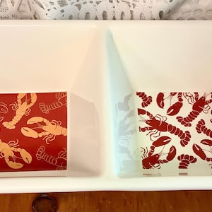 Puede incluir: Una fuente rectangular blanca con dos compartimentos. Cada compartimento tiene un azulejo cuadrado con fondo rojo y diseño de langosta. Un azulejo tiene langostas doradas, el otro tiene langostas rojas.