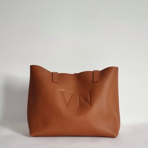 tan leather tote bag engraved with the initials VN in capital letters