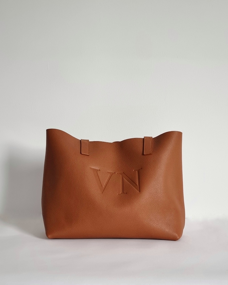 tan leather tote bag engraved with the initials VN in capital letters