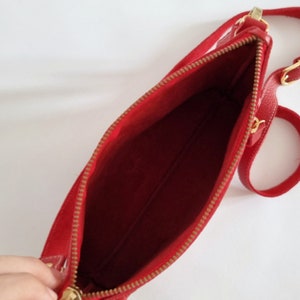 the inside of the crossbody bag is shown, without lining or interior pockets. This bag has zipper closure on its main side and also on its small outside pocket.