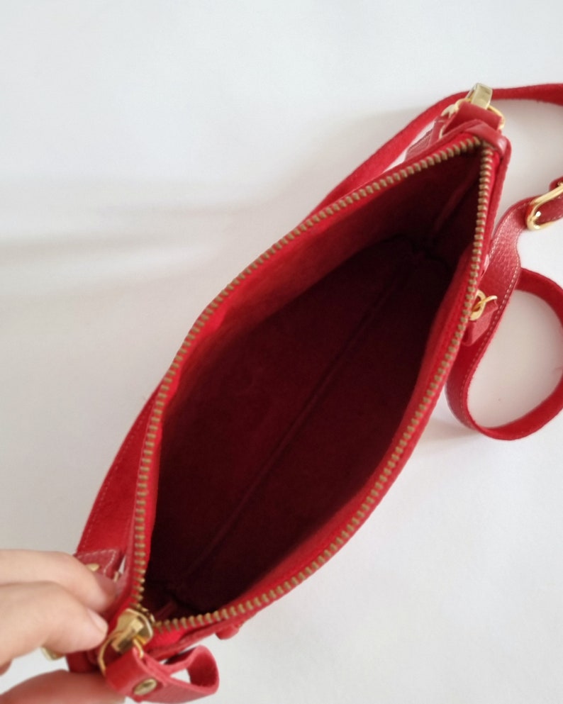 the inside of the crossbody bag is shown, without lining or interior pockets. This bag has zipper closure on its main side and also on its small outside pocket.