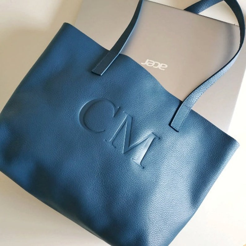 leather tote bag with a laptop inside to show its capacity.